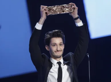L'acteur Pierre Niney soulevant son trophée lors de la cérémonie des César 2015.