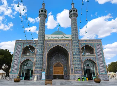 واجهة مزار ديني في كاشمر يتميز بمنارتين شاهقتين وزخارف إسلامية زرقاء.