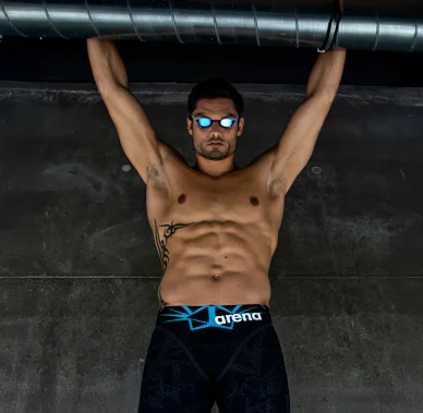 Florent Manaudou lors d’une séance photo sportive. Florent Manaudou pose en lunettes de natation et maillot noir.