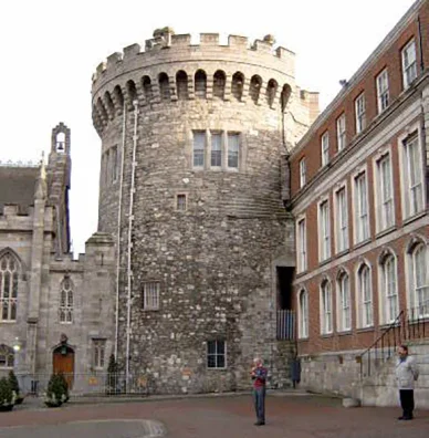 The medieval Record Tower at Dublin Castle, built around 1228, standing prominently with the Chapel Royal positioned to its left, both structures viewed from the Lower Courtyard.
